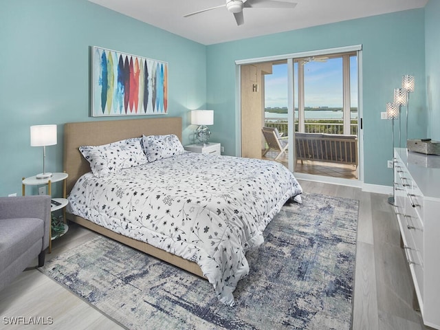 bedroom featuring access to exterior, ceiling fan, a water view, and light wood-type flooring