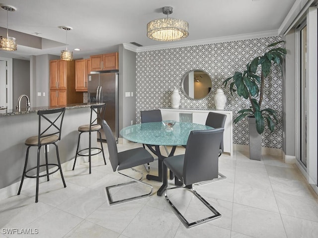 dining space featuring a chandelier, ornamental molding, and sink