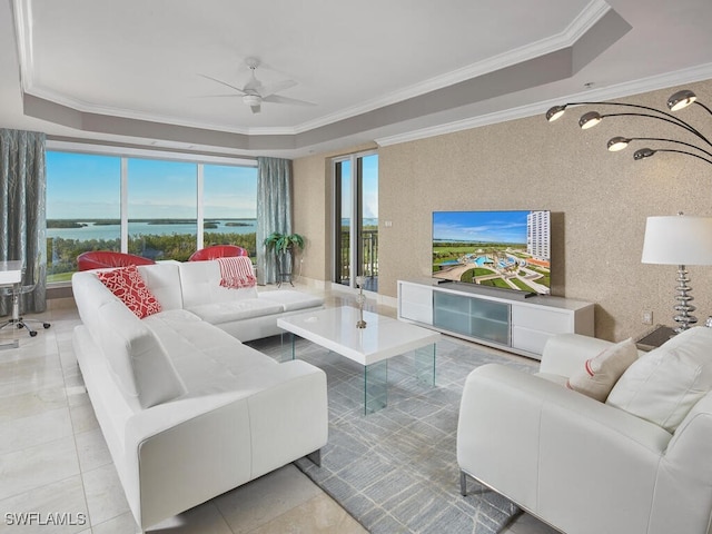 tiled living room featuring a tray ceiling, ceiling fan, and crown molding