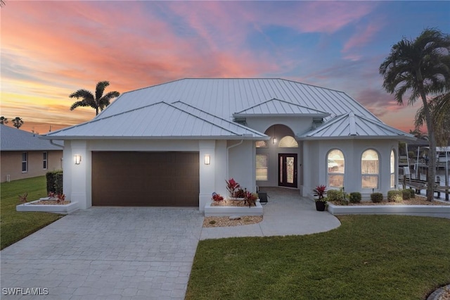 view of front of property featuring metal roof, a garage, decorative driveway, stucco siding, and a standing seam roof