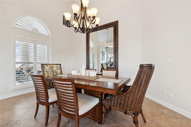 tiled dining room featuring a towering ceiling and a chandelier