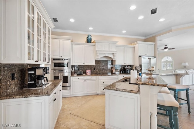 kitchen featuring stainless steel appliances, a center island with sink, glass insert cabinets, and white cabinets