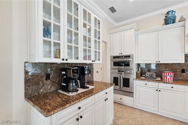 kitchen featuring dark stone countertops, double oven, glass insert cabinets, and white cabinetry