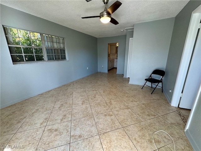 spare room featuring tile patterned flooring, baseboards, ceiling fan, and a textured ceiling