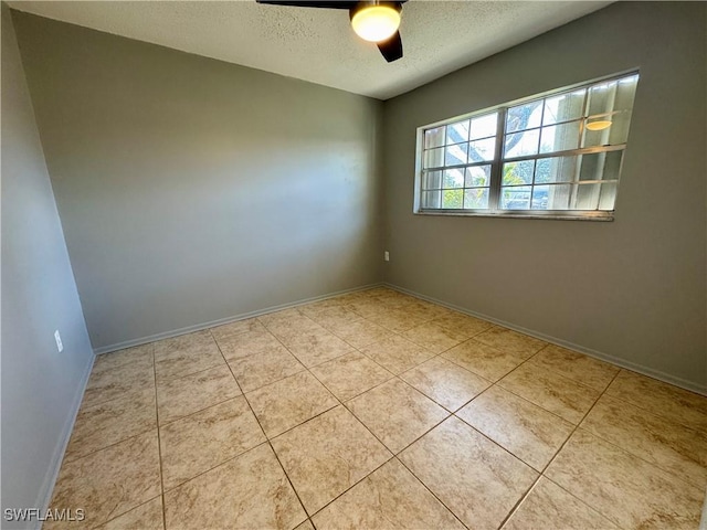 tiled spare room with a textured ceiling, a ceiling fan, and baseboards