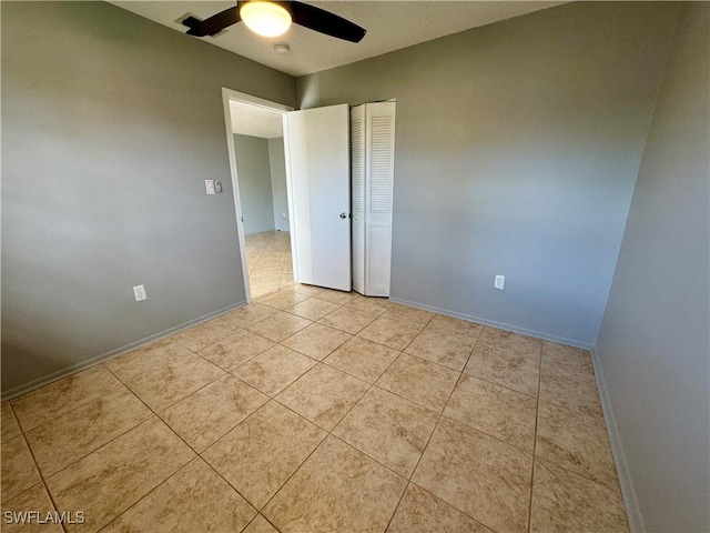 unfurnished room with light tile patterned floors, ceiling fan, and baseboards