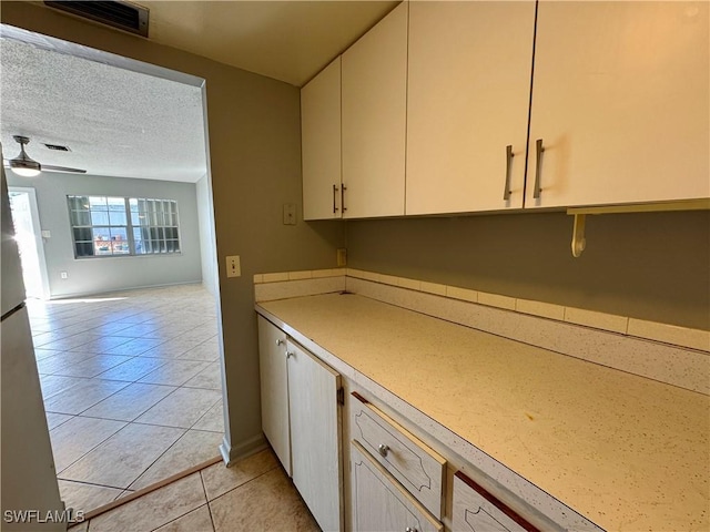 kitchen with light tile patterned floors, visible vents, ceiling fan, open floor plan, and a textured ceiling