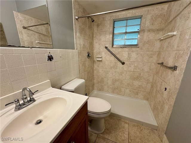 bathroom with tiled shower, toilet, tile patterned floors, vanity, and tile walls