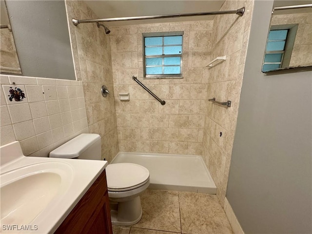 bathroom featuring tile walls, toilet, vanity, tile patterned flooring, and tiled shower