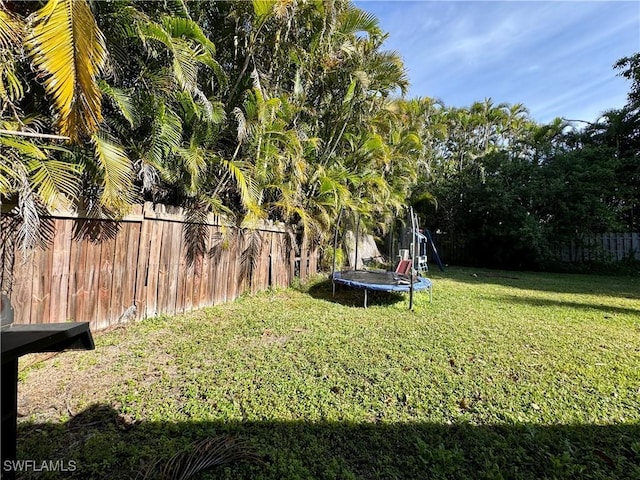 view of yard featuring a trampoline and fence