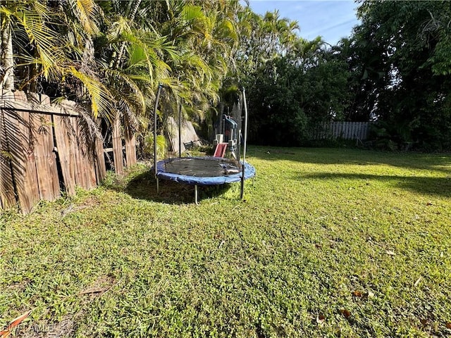 view of yard with a trampoline and a fenced backyard