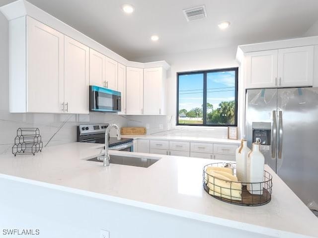 kitchen featuring kitchen peninsula, white cabinetry, and stainless steel appliances