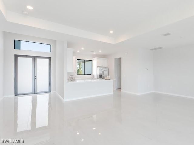 unfurnished living room with french doors and a tray ceiling