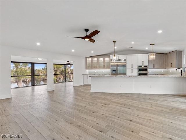 interior space with appliances with stainless steel finishes, lofted ceiling, sink, hanging light fixtures, and ceiling fan