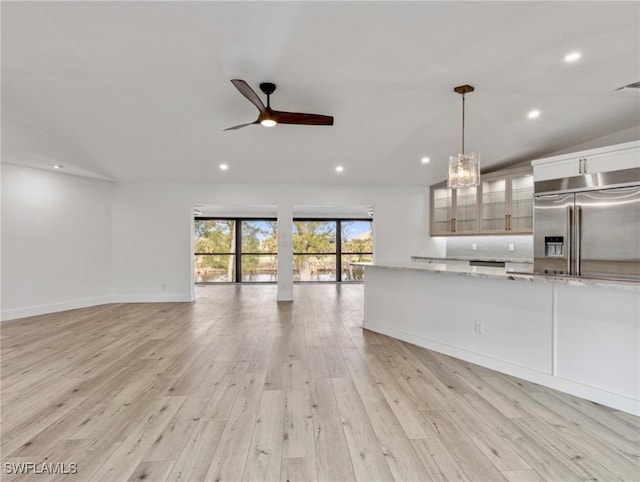 kitchen with ceiling fan, light stone countertops, white cabinets, decorative light fixtures, and built in fridge