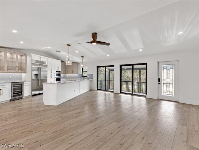 kitchen with wine cooler, hanging light fixtures, white cabinets, and appliances with stainless steel finishes