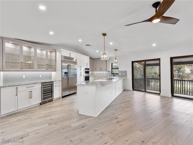 kitchen featuring wine cooler, stainless steel appliances, hanging light fixtures, and white cabinets