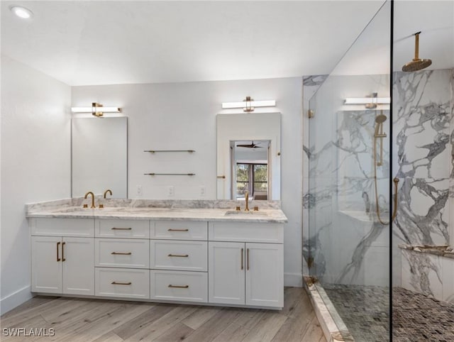 bathroom with tiled shower, vanity, and wood-type flooring