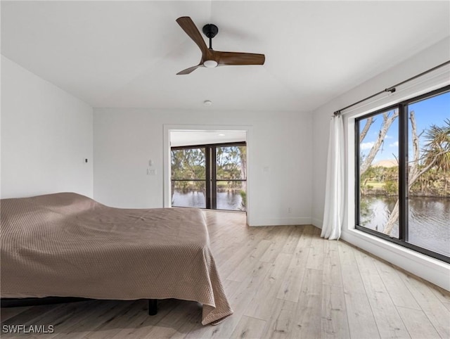 unfurnished bedroom with a water view, ceiling fan, multiple windows, and light hardwood / wood-style flooring