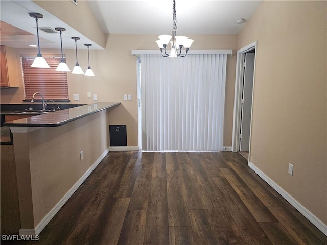 kitchen with kitchen peninsula, dark wood-type flooring, sink, decorative light fixtures, and an inviting chandelier