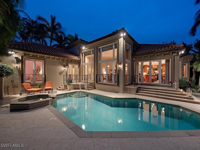 pool at twilight featuring an in ground hot tub and a patio