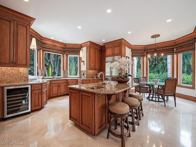 kitchen featuring beverage cooler, decorative light fixtures, stainless steel built in fridge, sink, and light stone counters