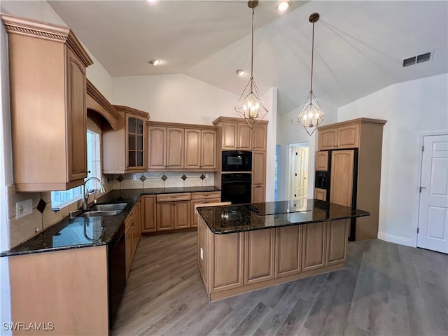 kitchen with black appliances, sink, hanging light fixtures, a kitchen island, and a chandelier