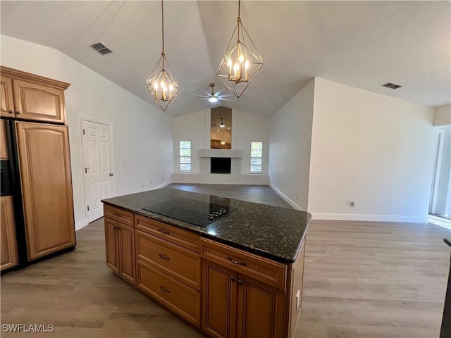 kitchen featuring a center island, hanging light fixtures, dark stone counters, vaulted ceiling, and black electric stovetop