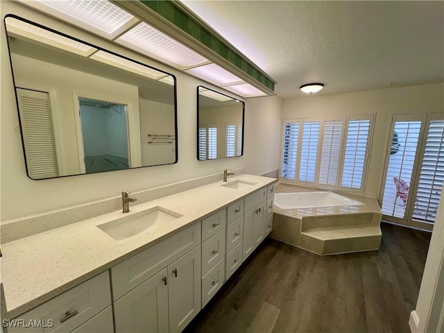 bathroom featuring vanity, wood-type flooring, and tiled tub