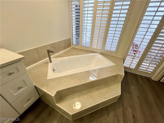 bathroom with vanity, wood-type flooring, and tiled tub