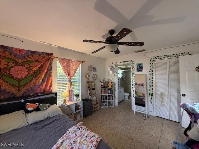 bedroom with ceiling fan, light tile patterned floors, and ensuite bath