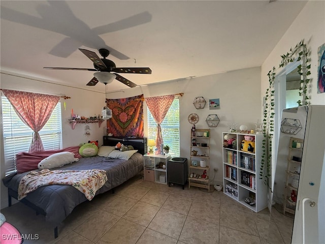 bedroom featuring ceiling fan, light tile patterned flooring, and multiple windows