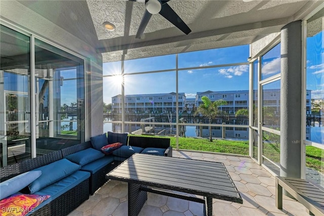 sunroom featuring ceiling fan and a water view