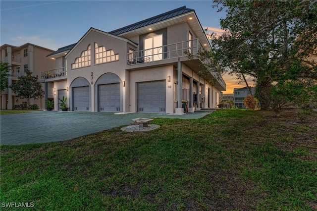 view of front of property with a garage, a balcony, and a yard