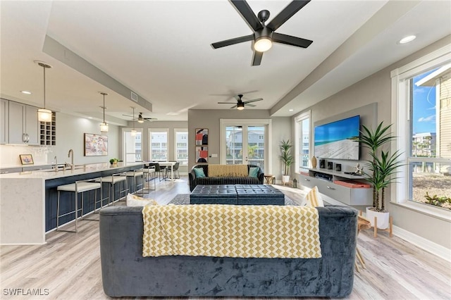 living room with ceiling fan, sink, and light hardwood / wood-style flooring