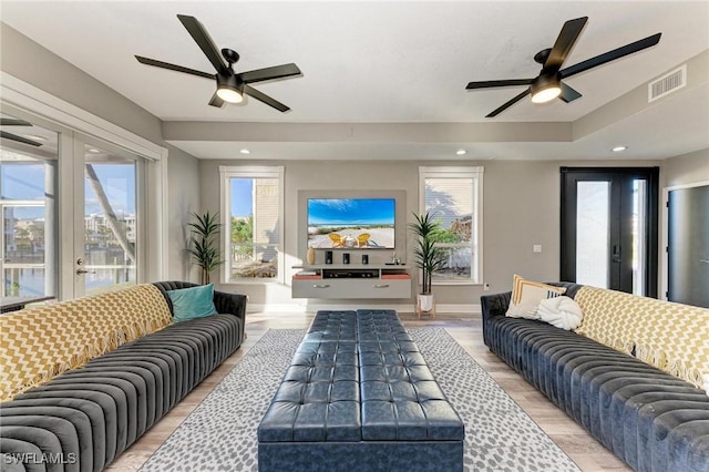 living room featuring ceiling fan, plenty of natural light, light hardwood / wood-style floors, and french doors