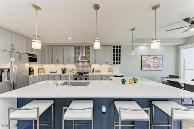 kitchen with a breakfast bar, wall chimney exhaust hood, and pendant lighting