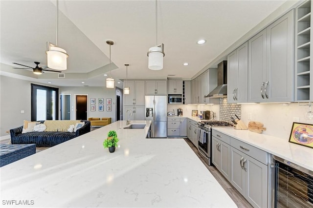 kitchen featuring gray cabinetry, pendant lighting, wall chimney exhaust hood, stainless steel appliances, and beverage cooler