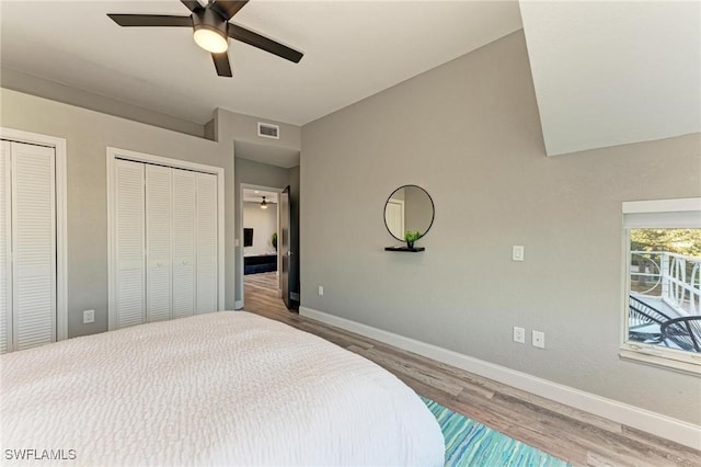 bedroom featuring ceiling fan, hardwood / wood-style floors, and two closets