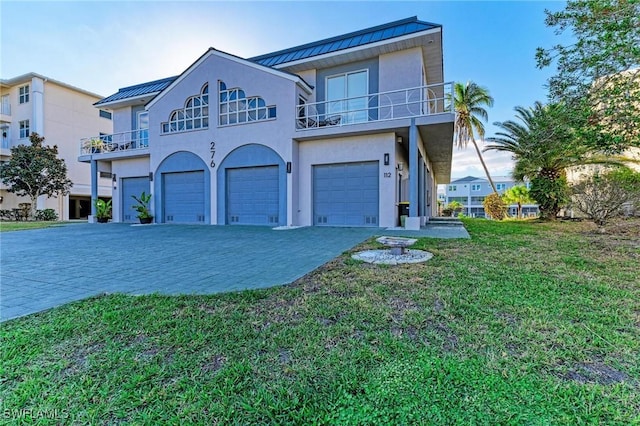 view of front of property featuring a balcony, a front lawn, and a garage