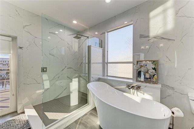 bathroom featuring plus walk in shower and tile walls