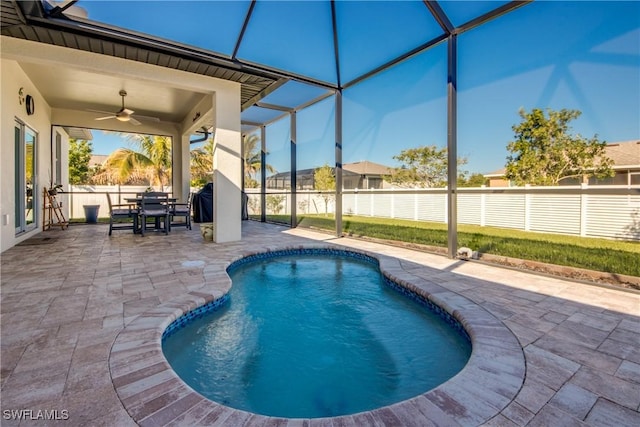 view of swimming pool with ceiling fan, a patio area, and glass enclosure