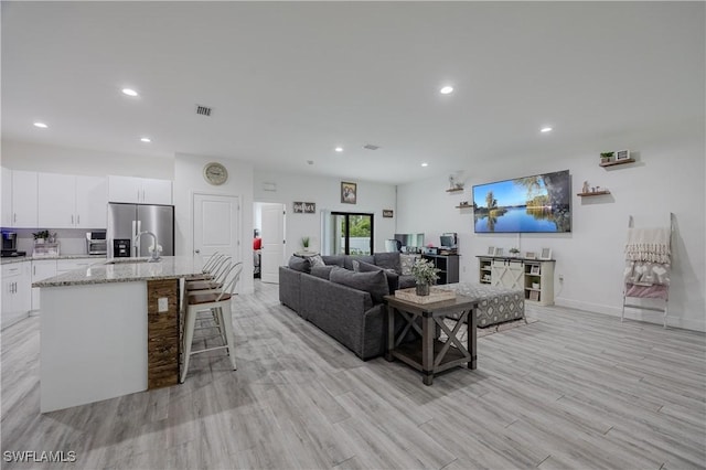 living room featuring sink and light hardwood / wood-style flooring