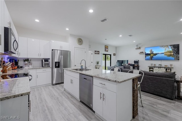 kitchen with white cabinetry, sink, an island with sink, light hardwood / wood-style floors, and appliances with stainless steel finishes