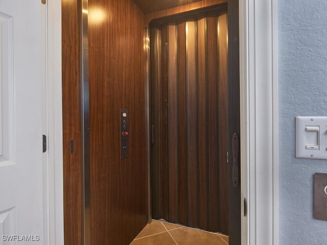 corridor with elevator and tile patterned floors