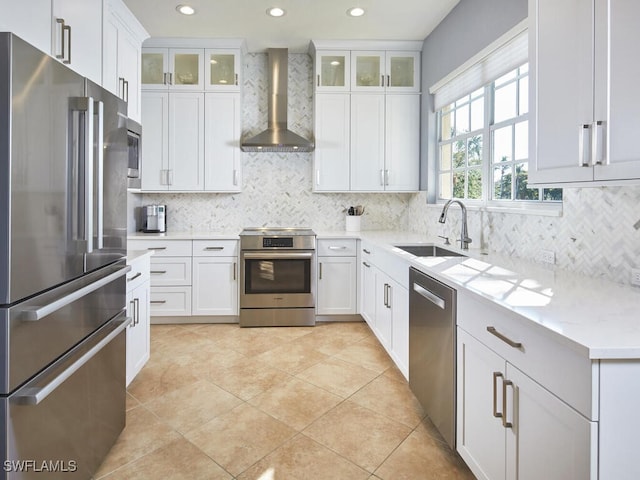 kitchen featuring white cabinetry, light stone countertops, wall chimney range hood, and appliances with stainless steel finishes