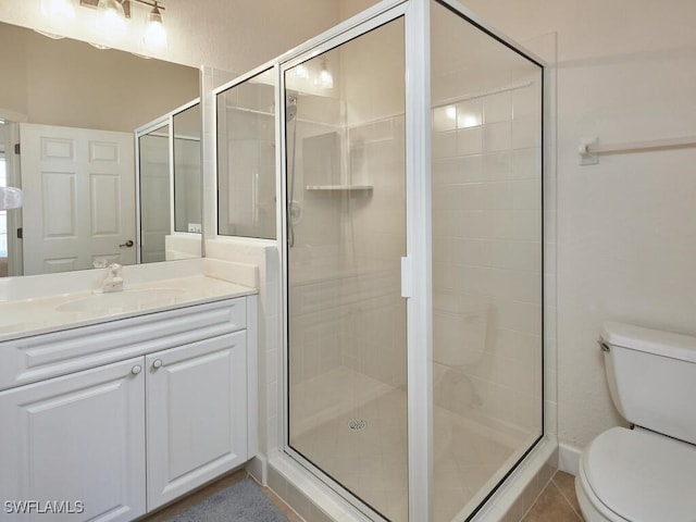 bathroom featuring toilet, vanity, tile patterned floors, and a shower with door