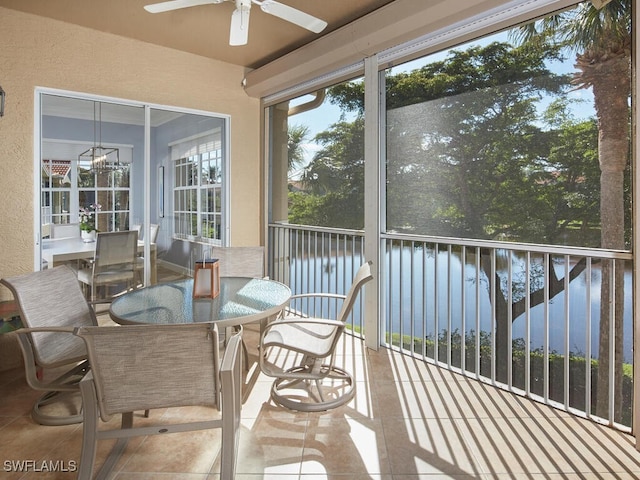 sunroom featuring ceiling fan and a water view