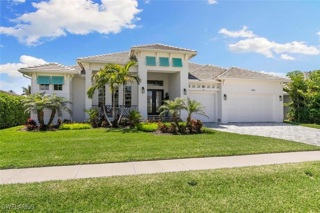 mediterranean / spanish-style home with french doors, a front lawn, and a garage