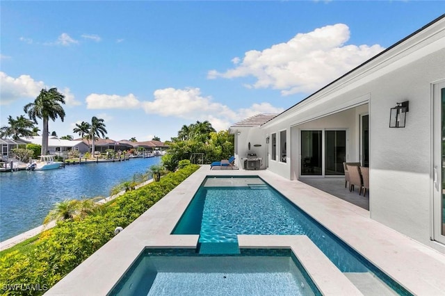 view of pool with a patio area, a water view, and an in ground hot tub